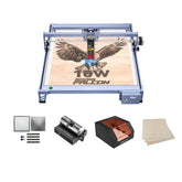The Creality Falcon 10W CR-Laser Engraver and Cutter etches an eagle and "10W Falcon" on wood. Accessories include metal sheets, a rotary roller, a black and orange enclosure, wooden boards, plus a free test kit.