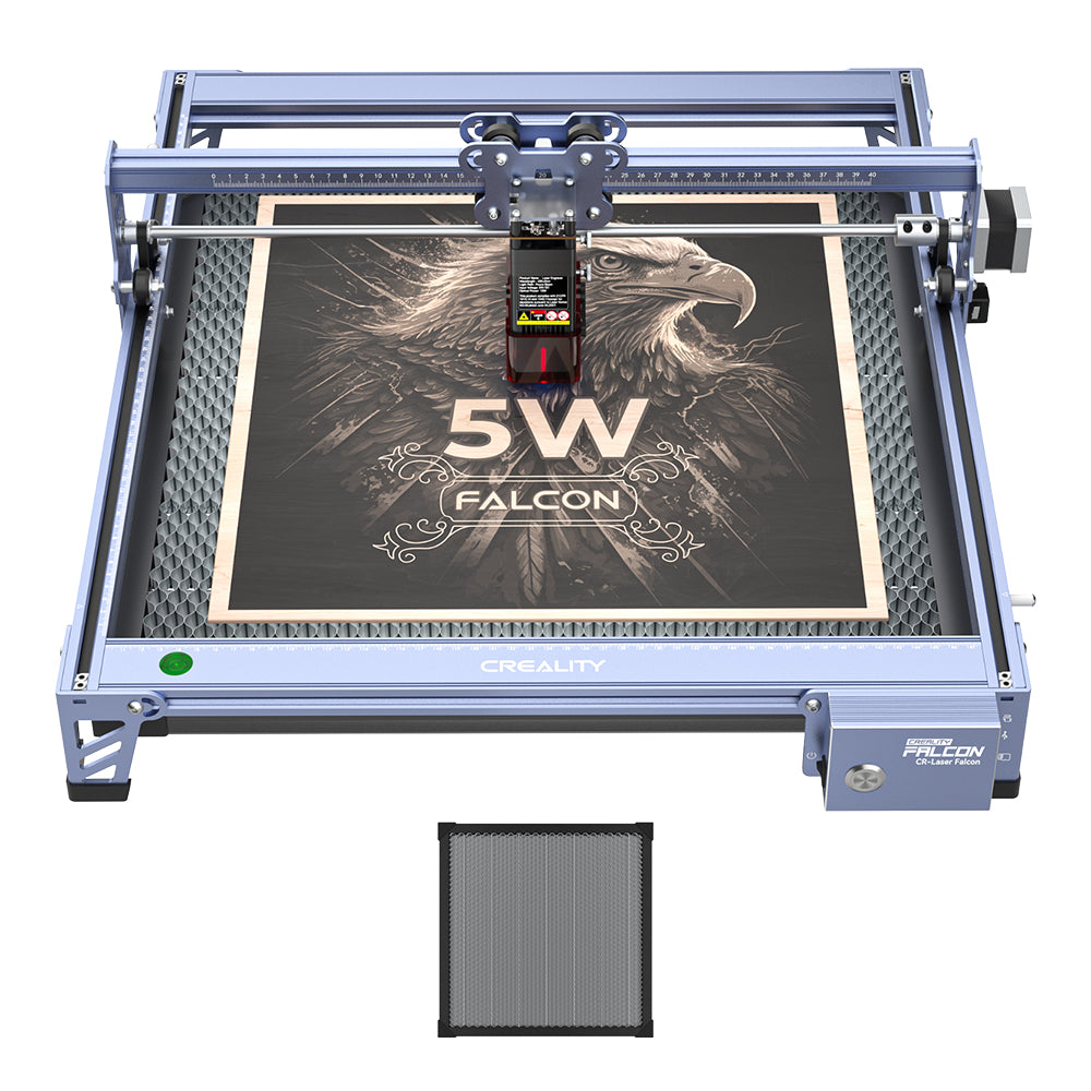The 5W CR-Laser Falcon Engraver and Cutter by Creality Falcon demonstrates its precise engraving by etching a detailed eagle and “5W Falcon” on wood, using a removable honeycomb panel for versatile materials.