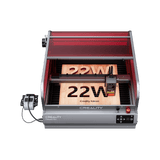 A Creality Falcon Falcon2 Pro 22W Enclosed Diode Laser Engraver with a visual positioning camera, red cover, control panel, FDA Class 1 safety, and external components engraves "22W" onto two wooden boards inside the machine. Includes free test kit.