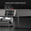 Close-up of a Creality Falcon2 3D printer featuring its control panel and part of a metallic cylinder adorned with a butterfly design. Above, the text "Work with Creality Falcon Risers for Falcon2 & Falcon2 Pro Series" is displayed, emphasizing its precision and adjustable height features.