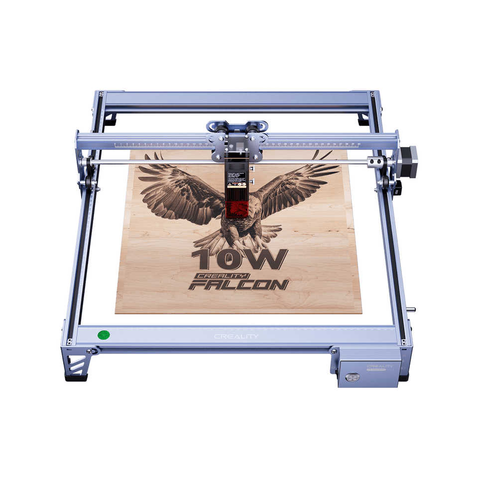 The compact Creality Falcon CR 5W Diode Laser Engraver etches a detailed eagle with outstretched wings and the text "Falcon CR 5W" onto a wooden board. The metallic, rectangular device is viewed from above. Free test kit included.