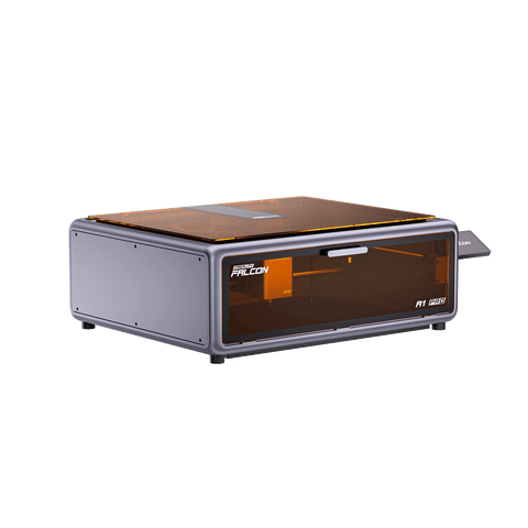 A compact, gray Creality Falcon A1 Pro 20W dual-laser engraver with an amber-tinted transparent lid and a front panel labeled "FALCON" and "F1 830," displayed on a white background.