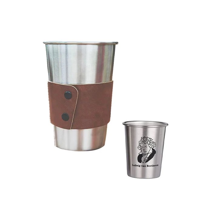 Two stainless steel cups from Creality Falcon's 500ML Stainless Steel Cups with Leather Covers - 4-Pack are displayed. The larger cup features a brown leather grip with two black buttons, and the smaller one, crafted from food-grade steel, includes a laser-engraved line drawing of Ludwig van Beethoven's face and name on its side.