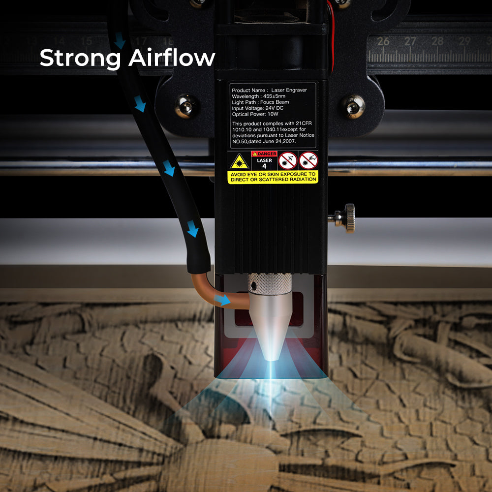 Close-up of a Creality Falcon Air Assist for CR-Laser Falcon 7.5W and 10W Engraver directing powerful airflow at a wooden surface. A bright laser beam is in action, surrounded by warning labels and specifications. Blue arrows show the airflow direction, maintaining low working noise while keeping material surfaces clean.