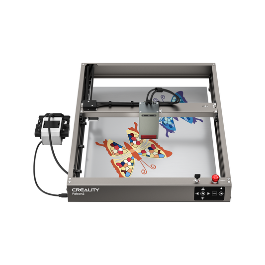 The Creality Falcon Falcon2 22W Laser Engraver and Cutter engraves colorful mosaic-patterned butterflies onto a flat surface, with control buttons and a rotary attachment visible on the left side. 1600