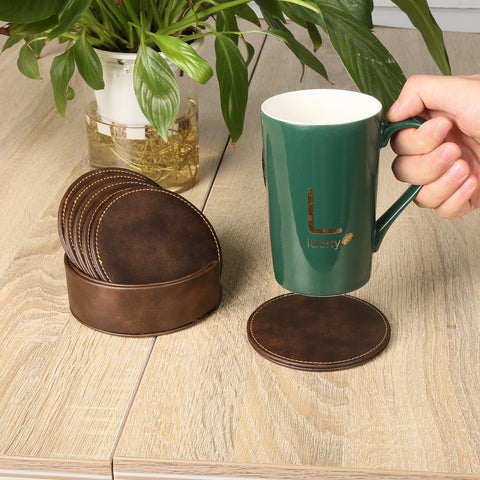 A hand places a green "Lucky" mug on a Creality Falcon leather coaster featuring elegant laser engraving. Nearby, similar coasters from the Personalized Brown Leather Coasters and Holder set of 6 add charm to the modern wooden table's look, complemented by a potted plant.