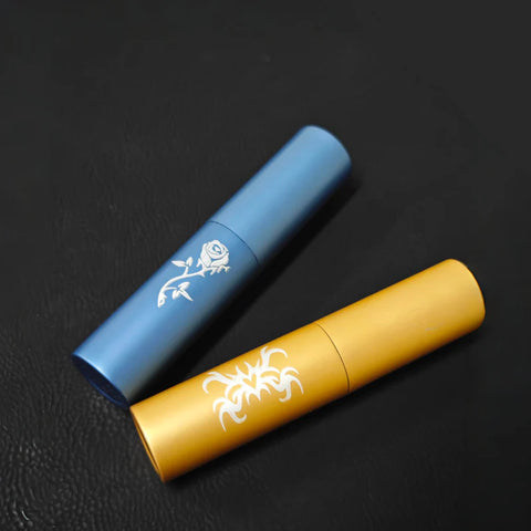 Two Creality Falcon atomizer bottles rest on a black surface. One is blue with a white rose design, and the other is yellow with a white tribal pattern, both sleek and closed, ready for any adventure.