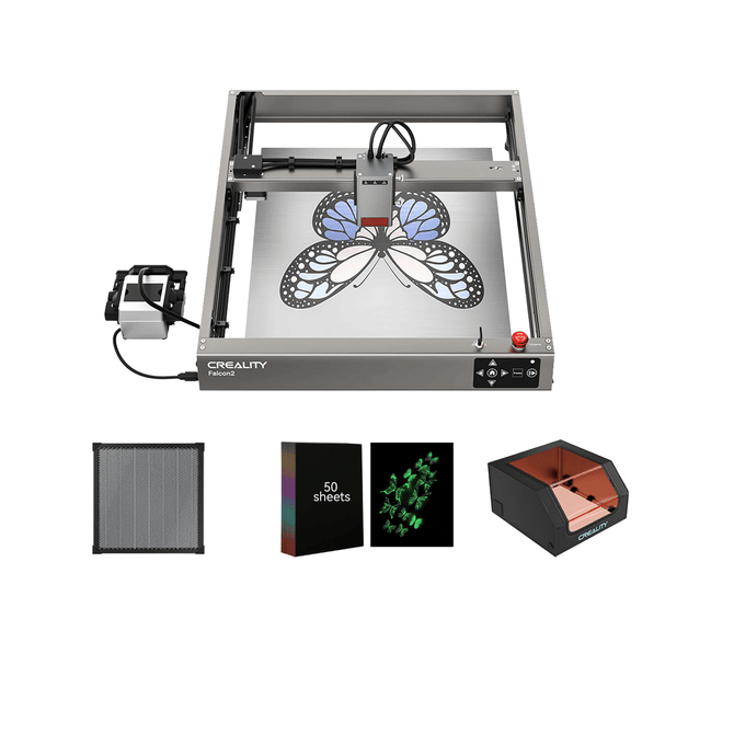 The Creality Falcon2 22W Diode Laser Engraver etches a butterfly on metal with built-in air assist, shown next to four accessories: a filter, a box labeled "50 sheets," green lens pieces, and a protective enclosure.